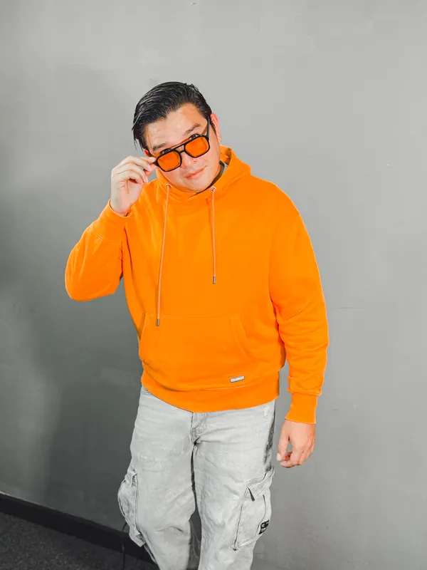 Retrato de Moi Milian con sudadera naranja y gafas